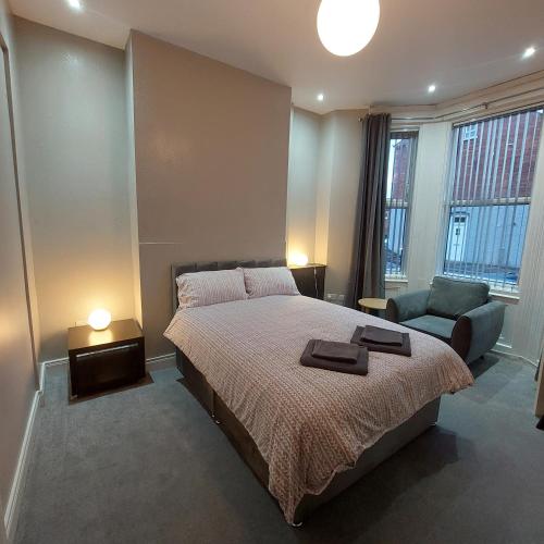 a bedroom with a bed and a chair and windows at Woodstock Townhouse Belfast in Belfast