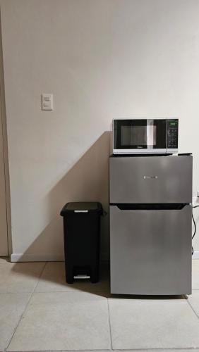 a microwave on top of a refrigerator with a trash can at Departamento Frontera #3 en el Campestre in Ciudad Juárez