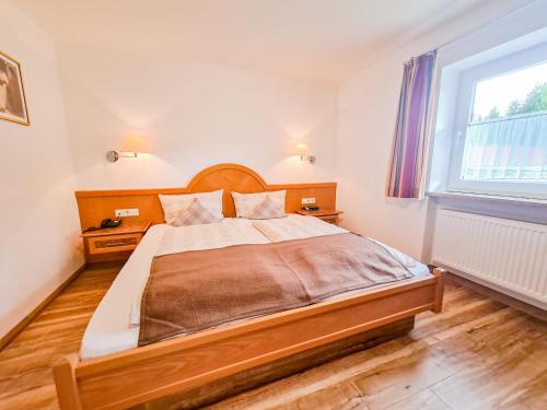 a bedroom with a large wooden bed with a window at Berghotel Sonnenklause in Sonthofen