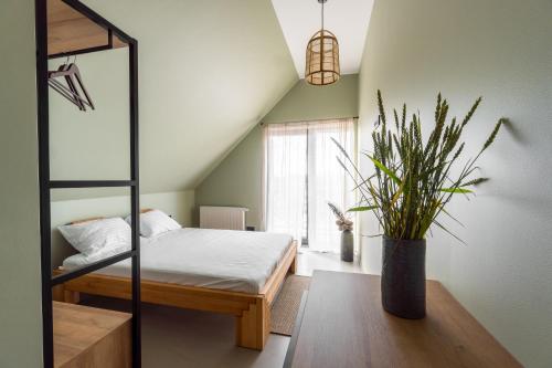 um quarto com uma cama e um vaso de plantas em Viešbutis SAKAI sodyboje Gribžė em Gribžiniai