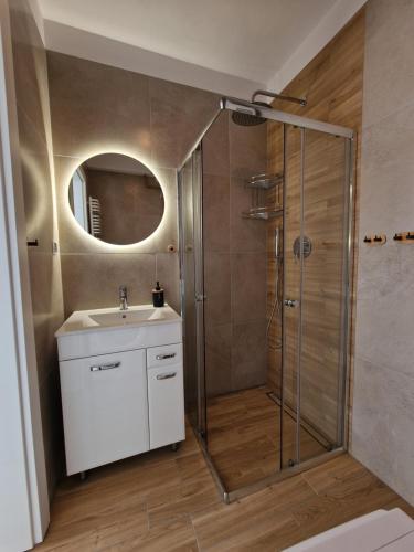 a bathroom with a shower and a sink and a mirror at Apartamenty Malaga II in Darłowo