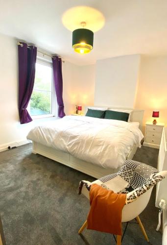 a bedroom with a bed and a chair and a window at Medway Getaway - 3 Bed Home with Luxury Bathroom in Chatham