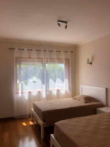 1 dormitorio con 2 camas y ventana en Casa Lirisol, en Fão