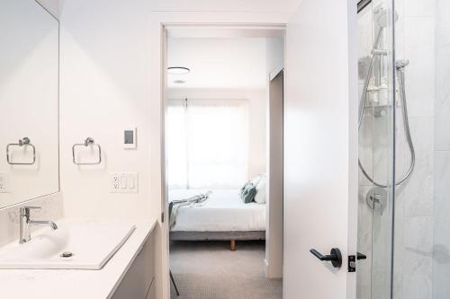 a white bathroom with a shower and a bed at Cabot Views by Revelstoke Vacations in Revelstoke
