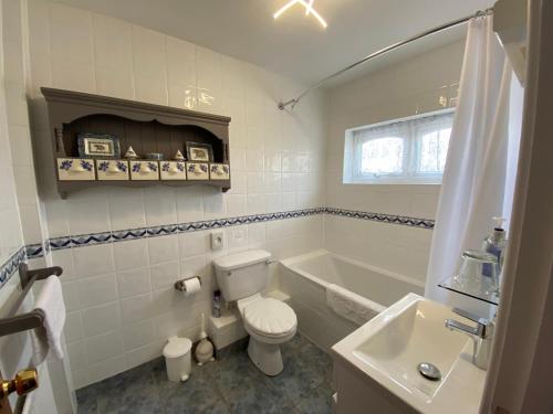 St Pierre du Bois的住宿－Beau Vallon Holiday Apartments，浴室配有卫生间、浴缸和水槽。