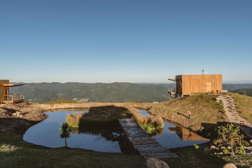 un puente sobre un estanque en la cima de una colina en Chalés de luxo na Serra Catarinense - VST, en Annitapolis