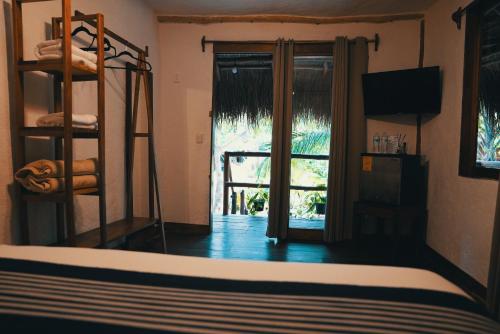 een slaapkamer met een stapelbed en een glazen schuifdeur bij Bluebayou Bacalar in Bacalar