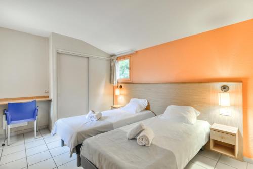 a hotel room with two beds and a blue chair at SOWELL HÔTELS Les Jardins du Cap in Cap d'Agde