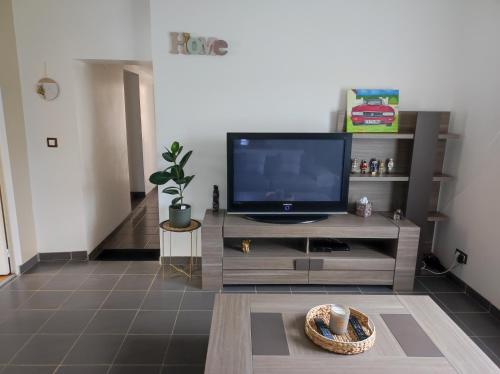 een woonkamer met een flatscreen-tv op een entertainmentcentrum bij Magnifique maison Dans un village du Vexin in Ableiges