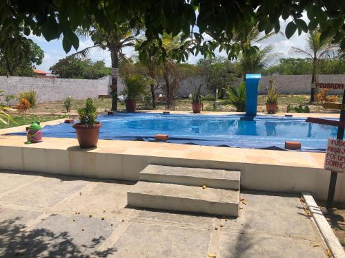 a large swimming pool with stairs and potted plants at Pousada Chácara do Coqueiro in Barreirinhas