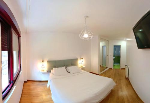 1 dormitorio con 1 cama blanca y TV de pantalla plana en Apartamento BarbanzaMar II, en Boiro