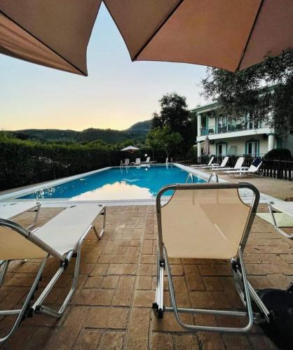 a swimming pool with two chairs and an umbrella at Harmony Garden in Parga