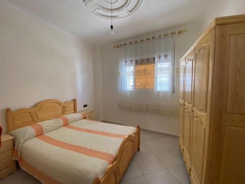 1 dormitorio con cama de madera y ventana en Appartement proche de la corniche en Alhucemas