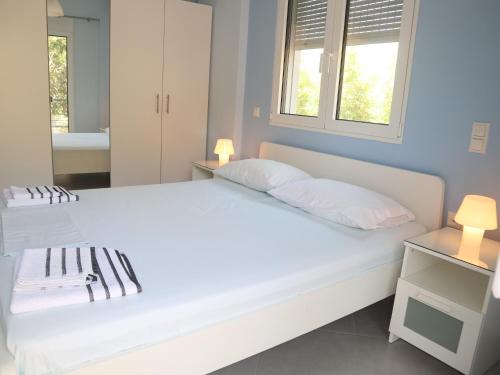 una camera da letto con un grande letto bianco con due cuscini di Patroclos SeaView a Sounio
