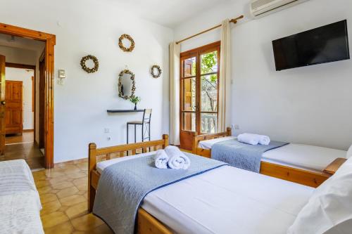 a room with two beds and a flat screen tv at Panagou Studios in Skopelos Town