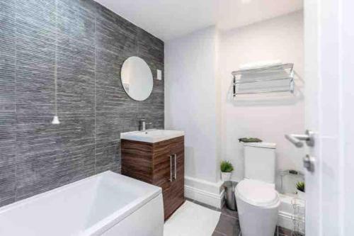 a bathroom with a tub and a toilet and a mirror at Beautiful 3 bedrooms apartment in London