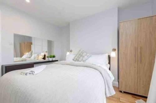 a white bedroom with a large bed and a wooden cabinet at Beautiful 3 bedrooms apartment in London