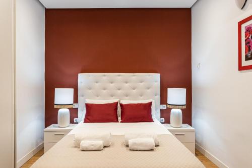 a bedroom with a large white bed with red pillows at BNBHolder Apartamentos en Sol Superior 2 in Madrid
