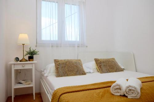 a white bedroom with a bed with towels on it at Holiday Home TiA in Split