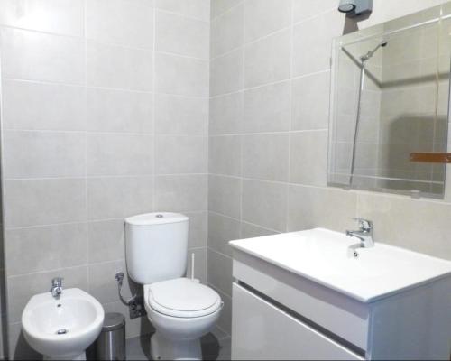 a white bathroom with a toilet and a sink at Your Home near the beach - Sesimbra in Sesimbra