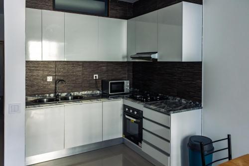 a white kitchen with a sink and a microwave at Apartamento Novo, Brand New Apartament T1, Cidadela, Praia, Cabo Verde in Praia
