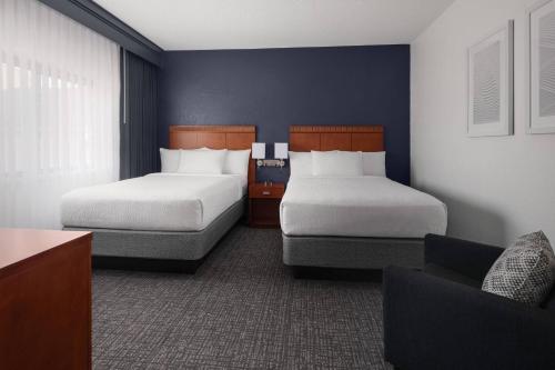 a hotel room with two beds and a chair at Courtyard by Marriott Rockville in Rockville