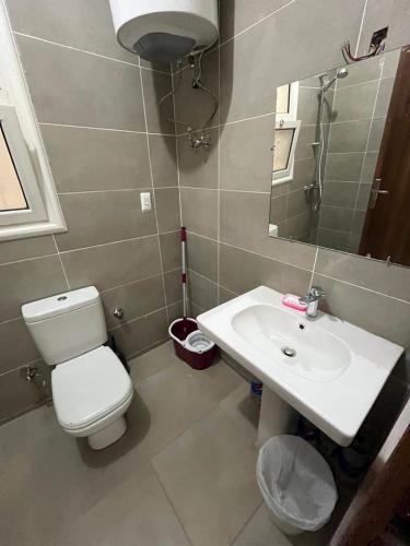 a bathroom with a toilet and a sink and a mirror at amwaj in Dawwār Ruḩayyim