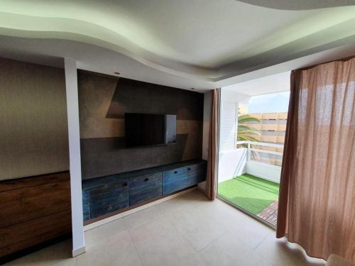 a living room with a flat screen tv on a wall at Hideaway Tenerife Holiday Apartment Las Américas in Playa Fañabe