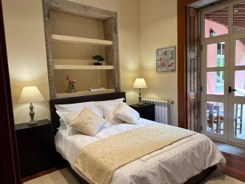 een slaapkamer met een bed met witte lakens en kussens bij Solar do Conde in Paredes de Coura