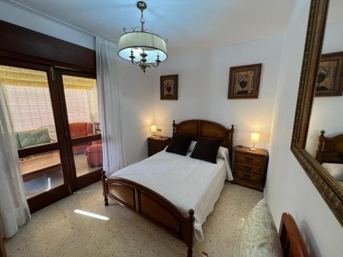 1 dormitorio con cama, espejo y lámpara de araña en Apartamento en Nanin-Sanxenxo, en Sanxenxo