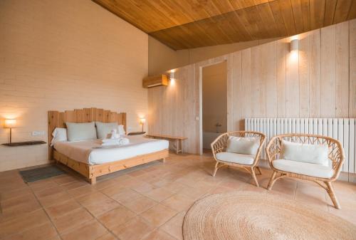 a bedroom with a bed and two chairs at ECOTurisme Can Buch HOTEL in Sant Aniol de Finestras
