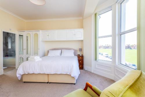 a bedroom with a white bed and two windows at The Priory House in Tynemouth