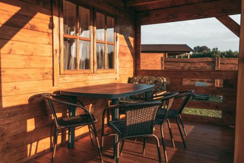 un tavolo e sedie sul portico di una cabina di Šeimos Namelis Adomo Sodyboje prie ežero 35 km nuo Vilniaus šalia Dubingių 