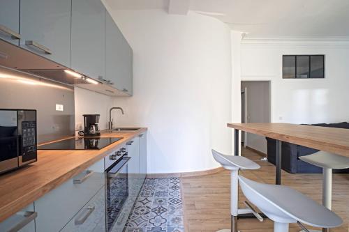 een keuken met witte kasten en een houten aanrecht bij L'Oasis de la Comédie, 4 Personnes, Parking Privé, Climatisation & Wifi in Montpellier