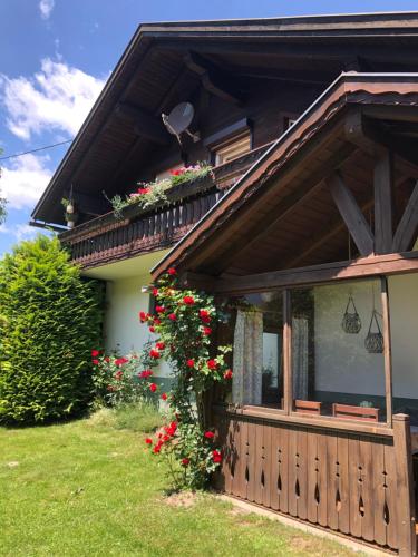 ein Haus mit einem Balkon mit roten Blumen darauf in der Unterkunft Ferienhaus Mautzfried in Reisach