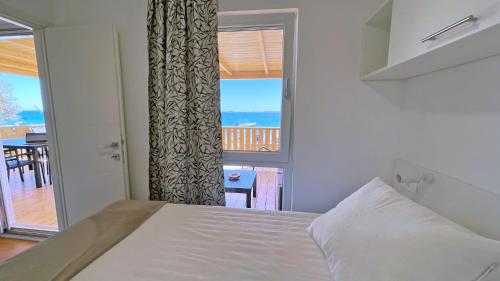 Schlafzimmer mit einem Bett und Blick auf einen Balkon in der Unterkunft Cottage JANICE Beach in Pakoštane