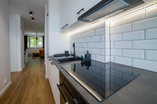 a kitchen with white tiles on the wall and a sink at Apartament Alpaka 1 in Lidzbark Warmiński