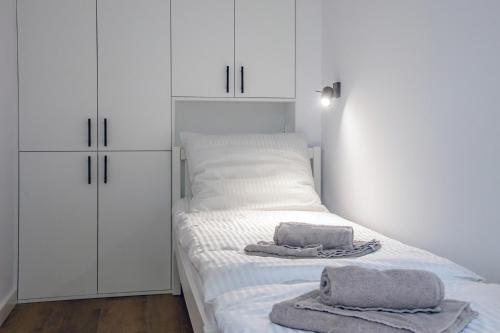 a bedroom with white cabinets and towels on a bed at Apartament Alpaka 1 in Lidzbark Warmiński