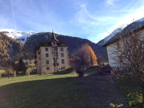 a large building in a field with mountains in the background at Hotel Schweizerhof Sta Maria in Sta Maria Val Müstair
