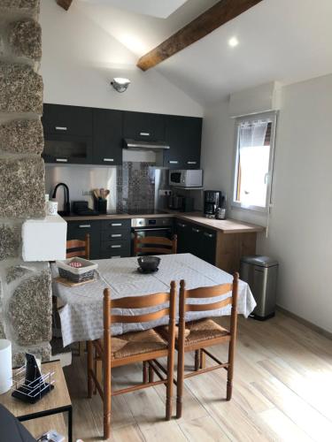 une cuisine avec une table et des chaises dans une pièce dans l'établissement Gite La Barthe Basse, à Le Pont-de-Montvert