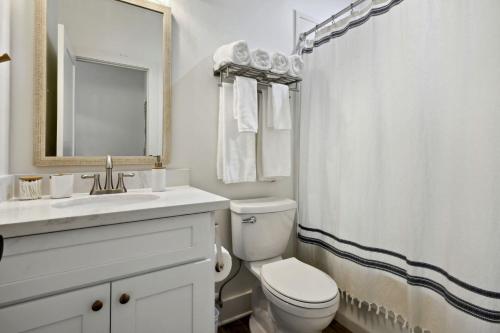 La salle de bains est pourvue de toilettes, d'un lavabo et d'un miroir. dans l'établissement Cozy Vacation Rental in Old Town Bay St Louis close to beach, bars, and dining, à Bay Saint Louis
