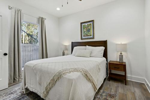 a white bedroom with a bed and a window at Cozy Vacation Rental in Old Town Bay St Louis close to beach, bars, and dining in Bay Saint Louis