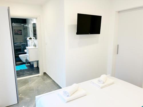 a white room with a tv and two white towels at Orhideja in Korčula