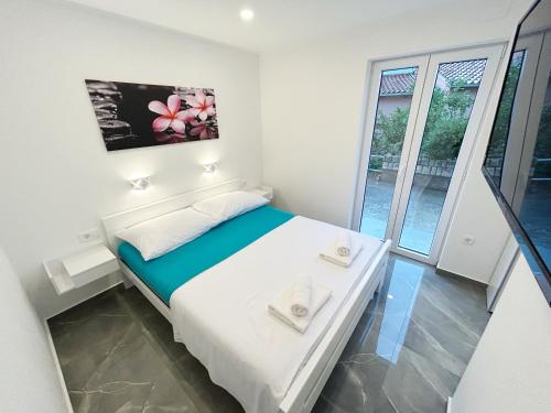 a small white bedroom with a bed and a window at Orhideja in Korčula
