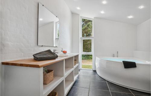 La salle de bains blanche est pourvue d'une baignoire et d'un lavabo. dans l'établissement Strandbo, à Thyholm