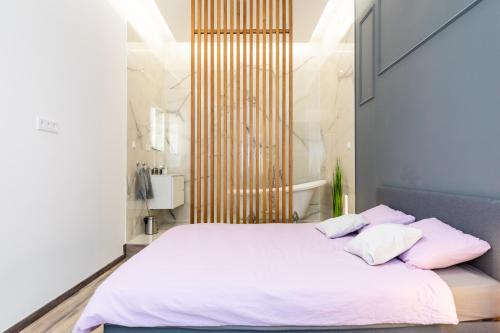a bedroom with a bed with white sheets and pink pillows at High end 2 bedroom apartment in downtown in Budapest