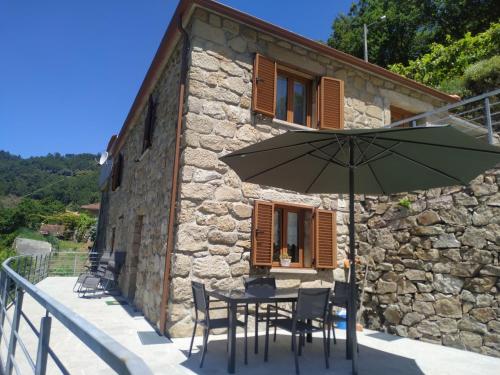 a table with an umbrella in front of a building at Casa da quintinha - Turismo rural in Arcos de Valdevez