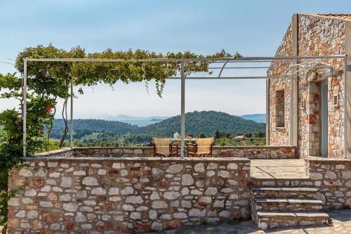 a stone building with a stone wall and a patio at Althea in Panormos Skopelos