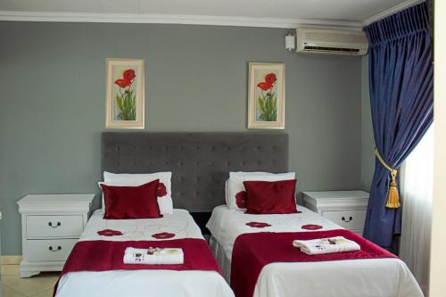 a bedroom with two beds with red and white sheets at Muofhe Graceland Lodge in Thohoyandou