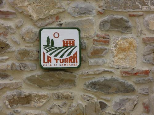ein Schild an der Seite einer Steinmauer in der Unterkunft La Turra - Casa di Campagna in Greve in Chianti